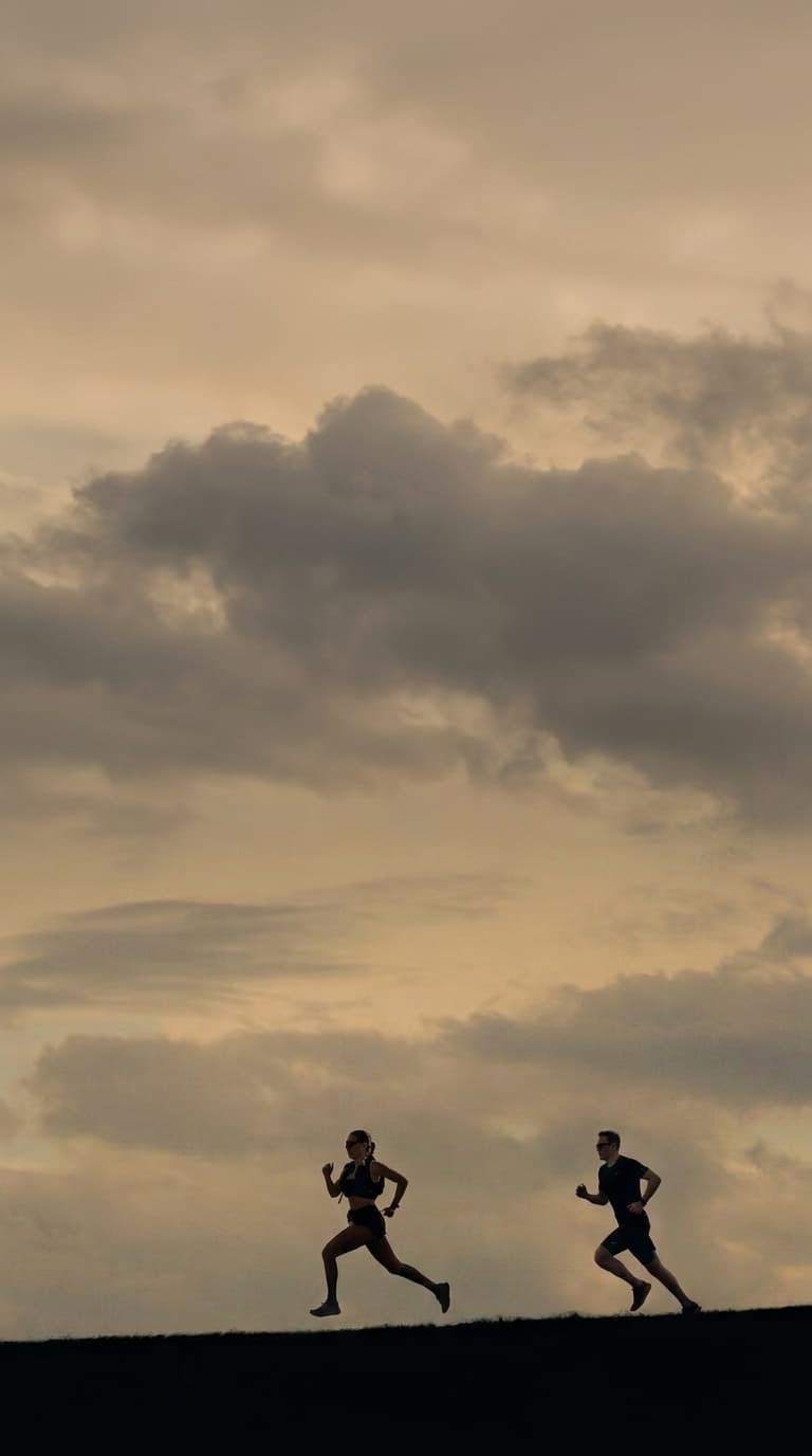 Two runners silhouetted on a ridge at dusk